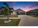 Exterior twilight view of well-maintained home featuring manicured lawn at 14525 Scottburgh Glen Dr, Wimauma, FL 33598