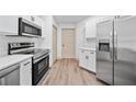 Modern kitchen with stainless steel appliances, ample cabinetry, and wood-look flooring at 1946 Hammocks Ave, Lutz, FL 33549