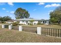 Wide exterior shot of well-maintained home featuring a dark metal and stone fence at 13000 Club Dr, Hudson, FL 34667