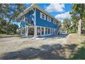 Bright blue raised home on stilts with a gravel yard and stair access to the second story at 10581 Pine Island Dr, Weeki Wachee, FL 34607