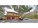 A two-story condo building with two-car garages, red doors, and surrounding landscaping at 2160 Chianti Pl # 11-0117, Palm Harbor, FL 34683