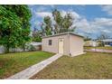 Backyard shed with a yellow door, set on a green lawn with a partial sidewalk leading to the entrance at 3916 W Oklahoma Ave, Tampa, FL 33616