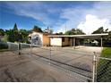 Exterior view of a single-story home featuring a gated driveway and a carport at 3916 W Oklahoma Ave, Tampa, FL 33616
