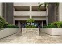 An exterior view showcasing the elegant entrance to Chateau Tower featuring lush landscaping at 7050 Sunset S Dr # 208, South Pasadena, FL 33707