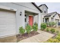 View of the front door with gray exterior, manicured lawn, and a two-car garage at 13456 Marble Sands Ct, Hudson, FL 34669