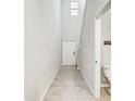 Bright hallway featuring tiled flooring, a stairway, and a glimpse of a bathroom, providing a sense of spaciousness at 13456 Marble Sands Ct, Hudson, FL 34669