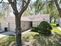 Street view of a single-story home featuring a well-kept lawn, a driveway, and mature trees at 35324 Whispering Pines Dr, Zephyrhills, FL 33541