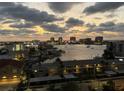 Scenic waterfront view featuring city skyline, waterfront homes with boat docks, and a colorful sunset sky at 400 Island Way # 903, Clearwater Beach, FL 33767