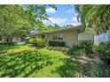Charming exterior showcasing a well-maintained lawn and garden beds shaded by mature trees and greenery at 216 21St Ne Ave, St Petersburg, FL 33704