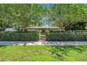 Inviting home featuring a manicured lawn and garden, partially concealed behind a lush privacy hedge at 216 21St Ne Ave, St Petersburg, FL 33704