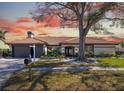 Inviting single-story home featuring a tile roof, mature trees, landscape, and a two-car garage with fresh exterior paint at 5809 Cruiser Way, Tampa, FL 33615
