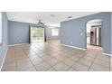 Open-concept living room boasts tile floors, a ceiling fan, gray walls, and sliding glass doors to the backyard at 10815 Wrigley Ct, Riverview, FL 33579