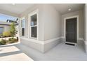 Covered front porch and entry featuring gray siding, white trim, and a dark front door at 12660 Glenn Creek Dr, Riverview, FL 33569