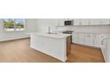 Modern kitchen features white cabinets, a kitchen island with quartz countertop, and stainless steel appliances at 12660 Glenn Creek Dr, Riverview, FL 33569