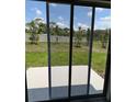 View of the backyard through sliding glass doors, showcasing a green lawn and privacy fence at 4648 Pleasant Ave, Palm Harbor, FL 34683