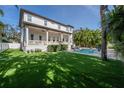 Spacious backyard featuring a covered patio, a swimming pool, lush tropical landscaping, and green lawn at 5020 W Dickens Ave, Tampa, FL 33629
