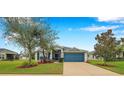 Charming single-story home featuring a well-maintained lawn, colorful landscaping, and a vibrant blue garage door at 5720 107Th E Ter, Parrish, FL 34219