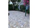 Paver driveway leading to a charming home with well-manicured landscaping and an American flag at 546 Orangewood Dr, Dunedin, FL 34698