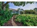 Landscaped front yard featuring lush foliage and a stone pathway leading to this delightful single Gathering home at 546 Orangewood Dr, Dunedin, FL 34698