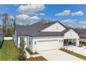 A beautiful home featuring a black roof, white exterior, two-car garage, and well-manicured lawn at 3739 Nandina Cir, Sun City Center, FL 33573