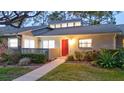 Inviting single-story home with a red door, landscaped garden, and warm exterior lighting at 40 Aster Pl, Oldsmar, FL 34677