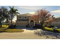 Inviting two-story home featuring a well-manicured lawn, mature trees, and an attached two-car garage at 8999 Founders Cir, Palmetto, FL 34221