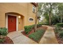 Inviting condo entrance with a red door, landscaped walkway, and neutral exterior at 2254 Chianti Pl # 68, Palm Harbor, FL 34683