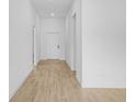 Bright hallway featuring light wood-look floors and white walls, leading to a doorway at 4294 Danbury St, North Port, FL 34286