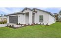 A modern white home with a two-car garage, green lawn, and walkway leading to the front door at 5710 Humkey St, North Port, FL 34291