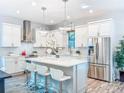 Bright kitchen with white cabinets, stainless steel appliances, an island with bar stools, and modern pendant lighting at 818 W Adalee St, Tampa, FL 33603