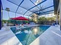 Inviting screened pool area featuring lounge chairs and a red umbrella for relaxing by the pool at 818 W Adalee St, Tampa, FL 33603
