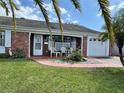 Charming single-story brick home with a well-maintained front yard and a cozy seating area on the porch at 3722 Haven Dr, New Port Richey, FL 34652