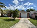 Cozy one-story home featuring a brick facade, a well-kept lawn, and an inviting driveway leading to the garage at 3722 Haven Dr, New Port Richey, FL 34652