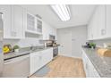 Bright kitchen featuring white cabinets, stainless steel appliances, granite countertops, and light wood-look flooring at 4519 S Hesperides St, Tampa, FL 33611