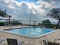 Community pool with a view of the lake on a partly cloudy day at 90 S Highland Ave # 423, Tarpon Springs, FL 34689