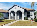 Welcoming home exterior showcasing arched entryway, light-grey stucco facade and landscaped front yard at 4209 Amber Ridge Ln, Valrico, FL 33594