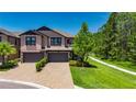 Elegant two-story townhome with a brick driveway and well-manicured landscaping in the daytime at 4899 Isola Ct, Wesley Chapel, FL 33543