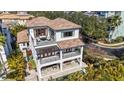 Stunning three-story home showcasing multiple balconies, a tile roof, lush landscaping, and a private pool at 4902 Carranza Ct, Tampa, FL 33616