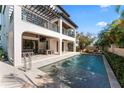 A luxurious backyard featuring a rectangular pool, covered patio, and meticulously manicured landscaping at 4902 Carranza Ct, Tampa, FL 33616