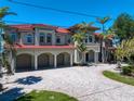 Stunning waterfront home with a red tile roof, covered parking, and meticulously landscaped grounds at 26 Sunset Bay Drive, Belleair, FL 33756