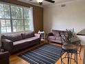 Inviting living room with large window, neutral colors, ceiling fan, and comfortable seating arrangement with striped rug at 501 Knights Run Ave # 2119, Tampa, FL 33602