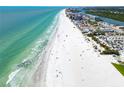 Stunning aerial view of a pristine beach with turquoise water, white sand, and nearby buildings at 17960 Gulf Blvd # 103, Redington Shores, FL 33708