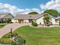 Charming single-story home boasts a lush lawn, mature landscaping, and a brick driveway at 1928 E View Dr, Sun City Center, FL 33573