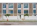 A modern townhome with large windows, light wood accents, and white privacy fence at 2702 N Woodrow Ave # 2, Tampa, FL 33602