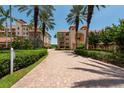 A stunning exterior view of the condo complex, showcasing its architecture, lush landscaping, and charming brick walkway at 1695 Pinellas Bayway S # E4, Tierra Verde, FL 33715