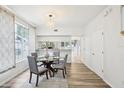 Bright dining room featuring hardwood floors, modern table and chairs, stylish light fixture, and large window at 2794 Countryside Blvd # 1, Clearwater, FL 33761