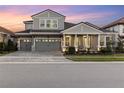Inviting two-story home featuring a three-car garage, brick driveway, and a cozy front porch area with seating at 14215 Swiss Bridge Dr, Riverview, FL 33579
