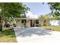 Charming single-story home with a well-manicured lawn, inviting red door, and a spacious driveway at 6145 55Th N Ave, St Petersburg, FL 33709