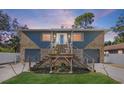 Unique two-story home with stone accents, dual garage doors, and elevated entryway with blue front door at 7418 Bay Dr, Tampa, FL 33635