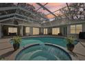 Enclosed patio featuring a swimming pool with attached spa surrounded by lush potted plants at 363 Sanctuary Dr, Crystal Beach, FL 34681